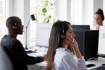 Woman wearing headset using desktop PC in office
