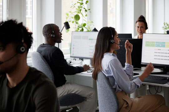 People working in call center office in front of desktop PCs