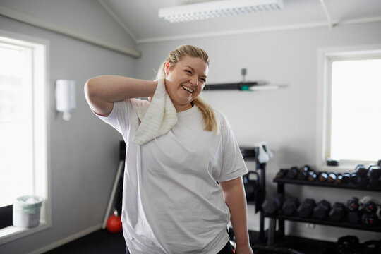 Happy woman drying neck with towel in gym