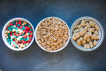 Variety of breakfast whole grain cereals and muesli in bowls on a light wooden background. Fast food. Top view. Space for text.