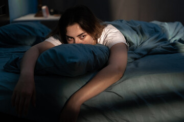 Sleep disorder, insomnia. Young woman lying on the bed awake at late night. Can not sleep - Powered by Adobe