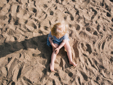 Blond girl sitting on sand