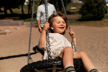 Smiling girl sitting on tire swing and swinging