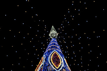 Vibrant Christmas tree light installation against a dark sky, brilliantly lit with a myriad of colorful lights