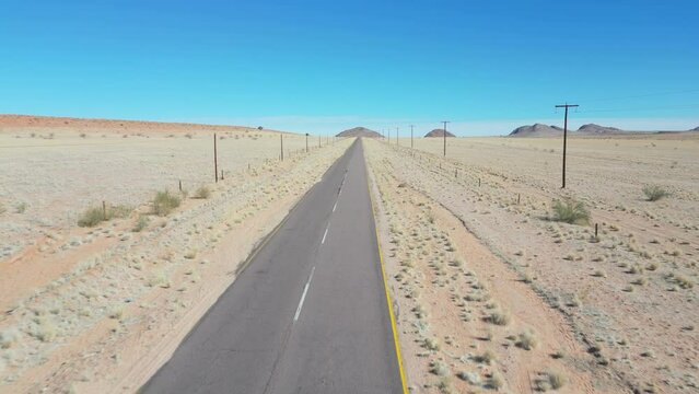 Fly along empty tar road in barren African desert landscape