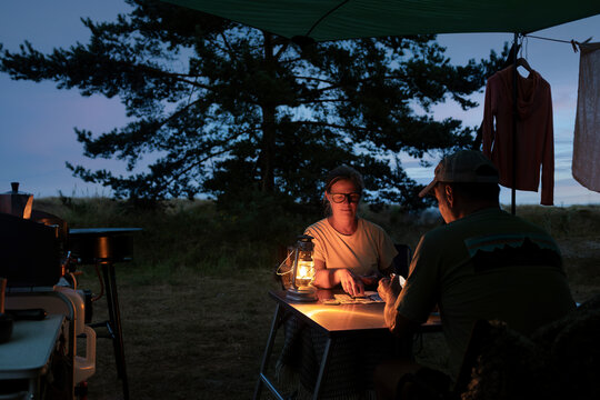 Couple playing cards while camping at dusk