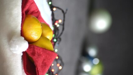 Christmas compsition, tangerines in red Santa Claus hat, vertical 4k footage. New year symbol