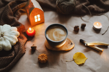 Autumn or winter cozy home interior with a cup, candles, plaid. Hygge home decor. 