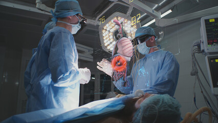 Doctors perform surgery in hospital operating room in VR headsets. 3D graphics of virtual holographic display showing vital signs and human organs. VFX animation. Innovative AI technology in medicine.