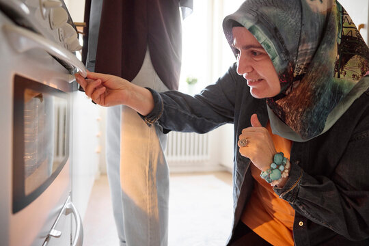 Woman checking food for eid al-fitr in oven