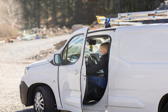 Smiling female technician sitting in van on sunny day