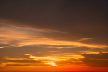 Fototapeta na wymiar 夕焼けの空に映る雲のグラデーション、深紅から明るいオレンジまでの色彩が美しい夜の幕開け
