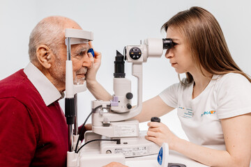 An ophthalmologist checks the vision of an elderly person using modern equipment. The concept of advertising ophthalmological services and medical technologies.