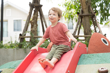 Fototapeta na wymiar Cheerful toddler little boy playing outdoor at playground in the park. Happy smiling little boy playing at playground