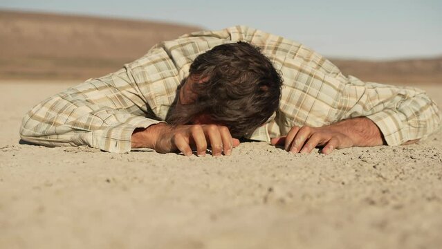 A man who survived the disaster lies face down on the dry ground and tries to crawl forward