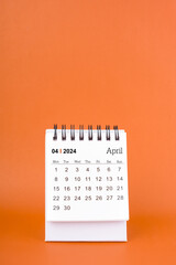April 2024 table calendar on orange color background.