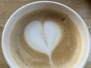 A cup of cappuccino with heart-shaped foam. Beautiful serving of coffee on the table in a...