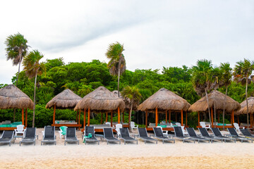 Palapa thatched roofs palms parasols sun loungers beach resort Mexico.
