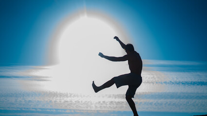 silhouette of a man who jumps while a parkour session