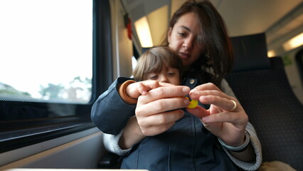 Focused mother guiding her son in counting during a train journey, embodying the essence of...