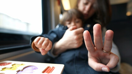 Focused mother guiding her son in counting during a train journey, embodying the essence of...