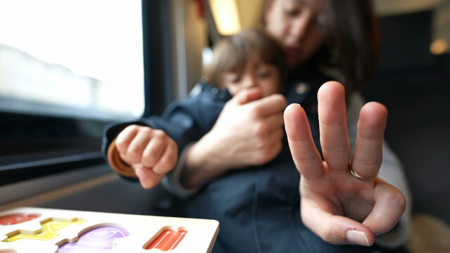Focused mother guiding her son in counting during a train journey, embodying the essence of homeschooling and childhood learning on-the-go