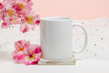 Mockup white mug on wooden cup coaster with pink lily flowers and fabric with glitter, copy space. Mockup mug for logo, gift and design.Valentine, mother day, women day, holiday theme