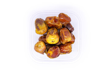 Close-up view of a large pile of delicious golden Sukkari dates in a transparent food container to keep food hygienic isolated on white background. Arabic healthy food concept.