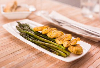 Fried chicken breast pieces with asparagus on white plate