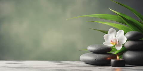 Zen stones, candles and white orchid flower on green and grey background with copy space, wellness...
