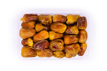 Close-up view of Transparent food container filled with Pile of large delicious Sukkari Ajwa dates to keep food hygienic isolated on white background. Arabic healthy food concept.