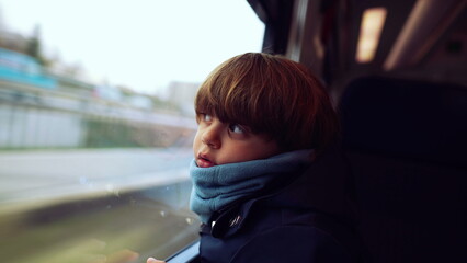 Introspective young boy with scarf, nestled by the train window, lost in contemplation as the...