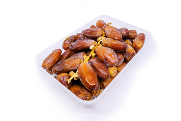 Close-up view of a Pile of large delicious Sukkari dates in a transparent food container to keep food hygienic isolated on white background. Arabic healthy food concept top view.