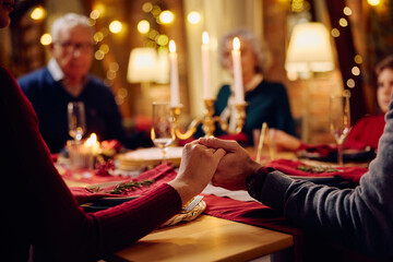Close up of couple saying grace during family dinner on Christmas Eve.