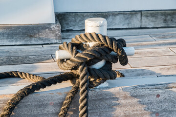 Old metal dock mooring pole with rope for securing fishing boats closeup