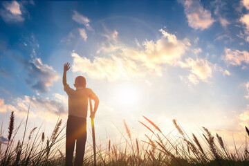 a disabled man standing up and raising his hand at  sunrise morning background