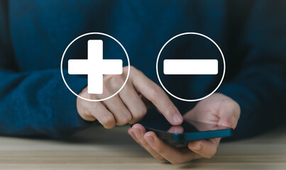 using the phone to show icons plus and minus, sign opposite negative positive. concept of the...
