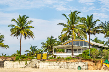 Fototapeta na wymiar coconut trees on ocean coast near tropical shack or open cafe on beach with sunbeds