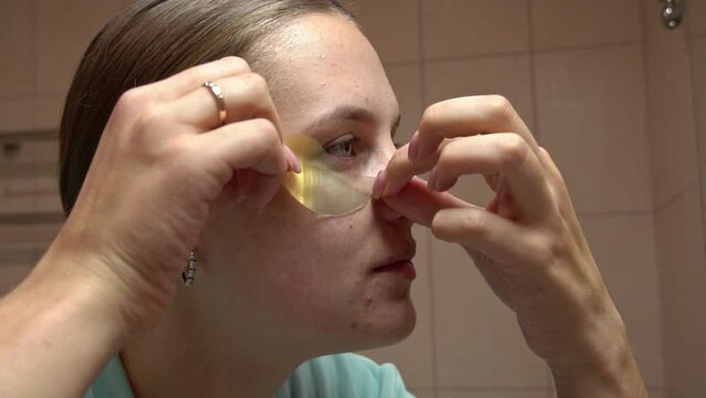 Girl does beauty treatments on her face close-up. Portrait of young girl who takes care of her face, cleanses her face with cotton pad, applies patches for the skin around her eyes, applies mask