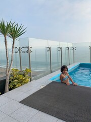 Fille dans piscine sur un rooftop au dessus de la plage