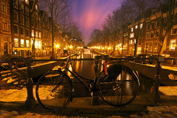 Fototapeta na wymiar Bicycle against a bridge in Amsterdam the Netherlands at night