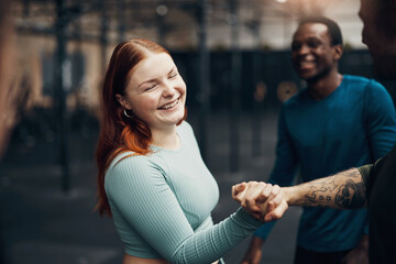 Woman laughing and shaking hands with a partner at the gym