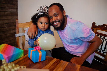 Fototapeta premium Young African father with biracial son celebrating his birthday and smiling into camera