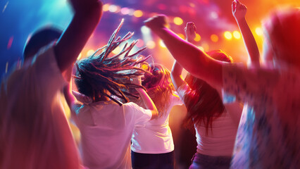 Happy, overjoyed people, students dancing raising hand and singing in neon light, spotlights indoor on party in motion blur.
