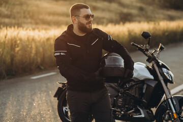 Man biker standing by his bike holding his helmet