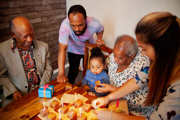 Multiracial family celebrating baby boy's birthday with presents and cake