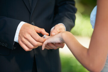 Couple, hands and wedding ring for proposal, commitment or promise in love, care or trust and support at ceremony. Closeup of married man putting jewelry on bride for loyalty, marriage or engagement