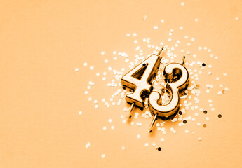 43 years birthday celebration festive background made with golden candle in the form of number Forty three lying on sparkles.