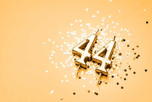 44 years birthday celebration festive background made with golden candle in the form of number Forty four lying on sparkles.