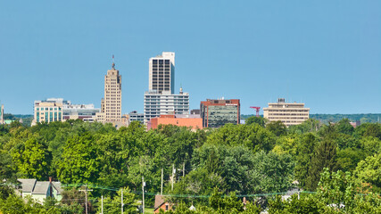 Fort Wayne downtown buildings with green forest line and clear blue skies aerial